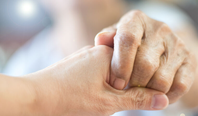 Close up of two elderly people holding hands.