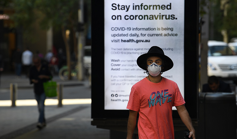 Man wearing mask in front of coronavirus PSA.