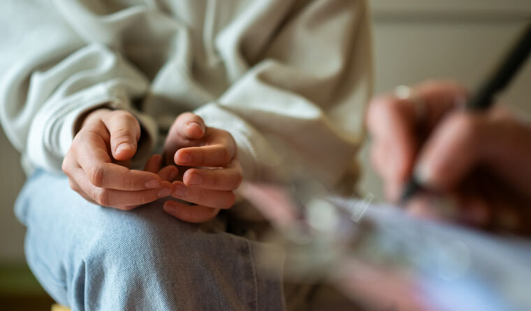 A person sitting anxious with hands on knees