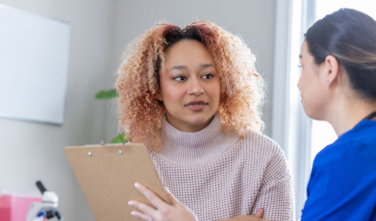 Young woman with curly hair sits opposite doctor