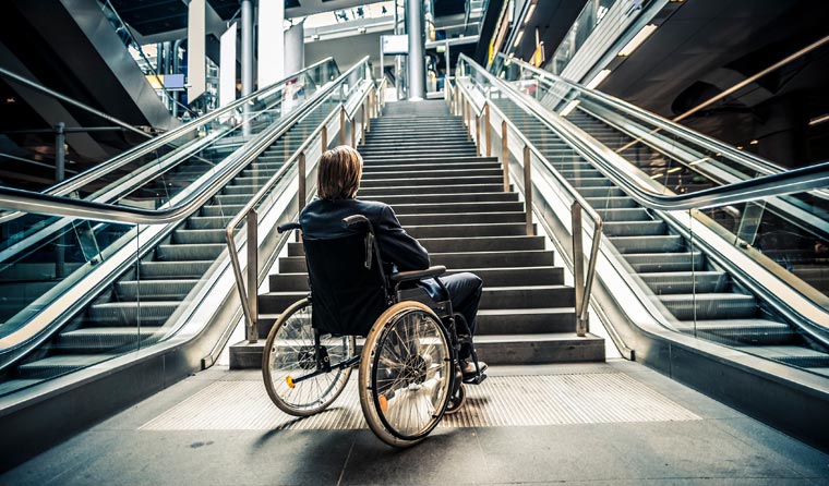 Man in wheelchair at bottom of escalators.