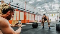 Man filming another man weight lifting.