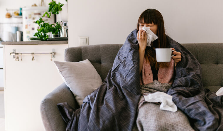 Woman sick on couch blowing her nose