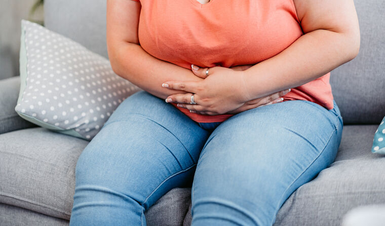 Overweight woman clutches stomach in pain.