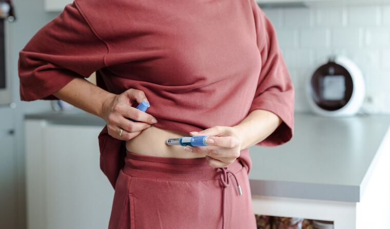 Woman injects medication into her belly.