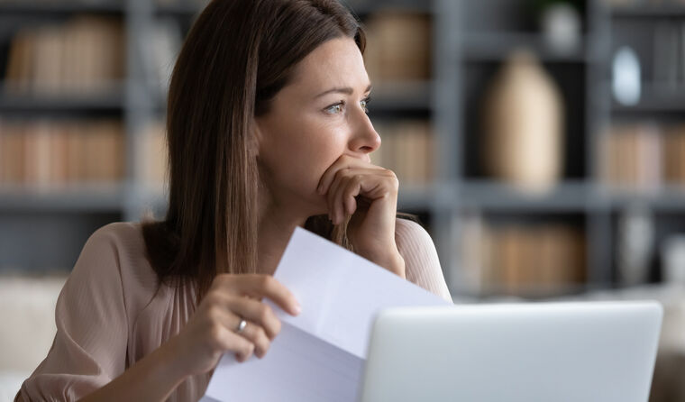 A female GP with letter in hand in front of laptop