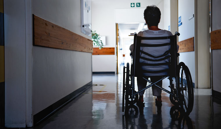 Elderly woman in a wheelchair in empty corridor