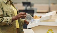 Person placing plastic bottle in to recycling bin
