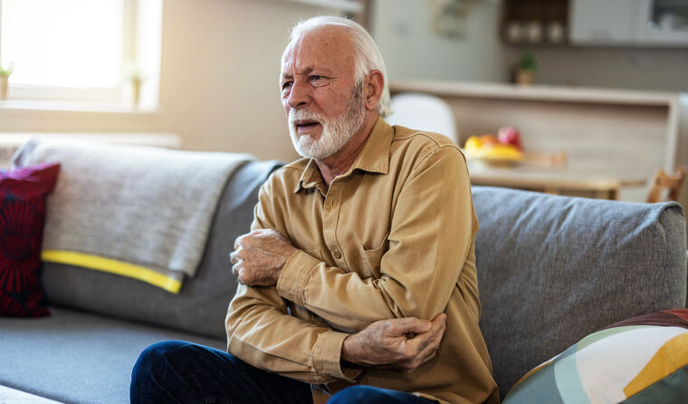 Older man holding arm in pain. 