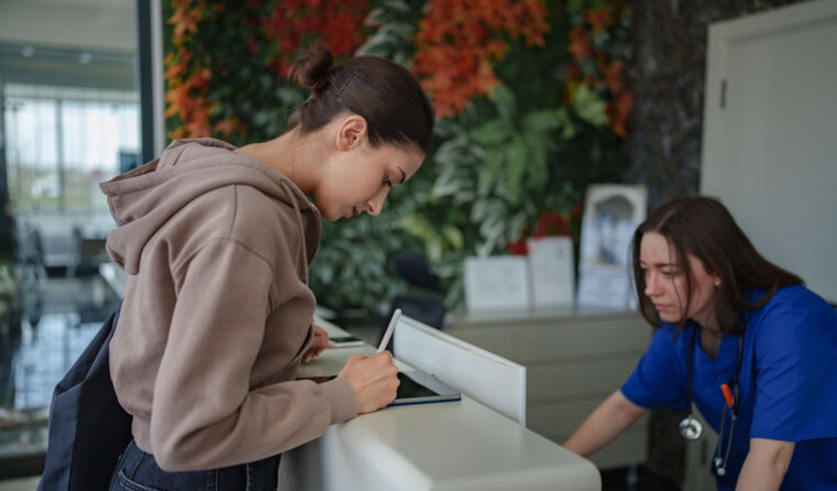 Patients signing at doctor's office desk.