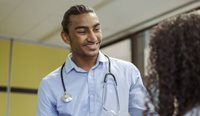 A young male doctor smiles at patient.