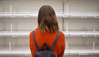 A young woman standing in front of empty shelves.