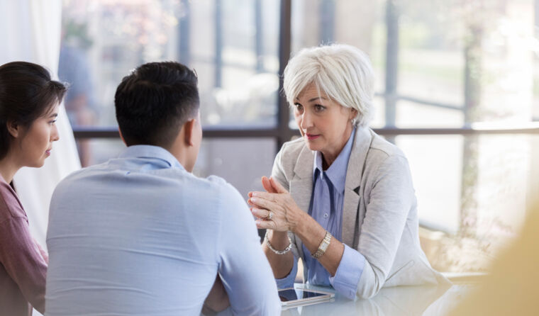 Older female doctor in serious talk with couple