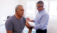 Aboriginal man receives vaccine in his arm from GP