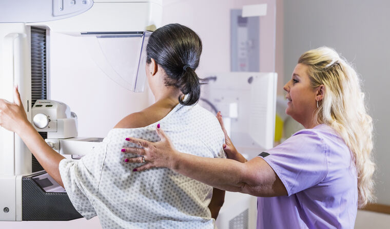 Doctor helping a woman get a mammogram.