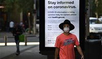 Man wearing mask in front of coronavirus PSA.