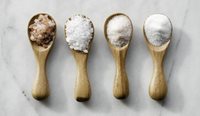 Four different types of salt sitting on spoons.