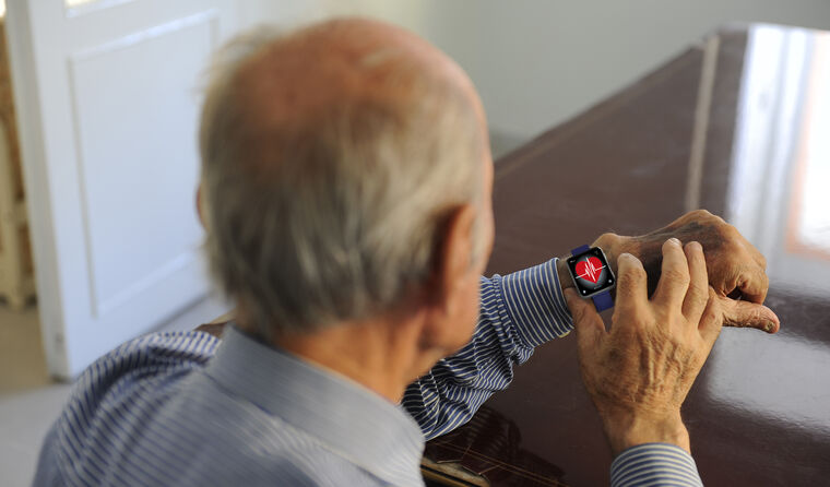 Elderly man looking at heartrate on smartwatch.