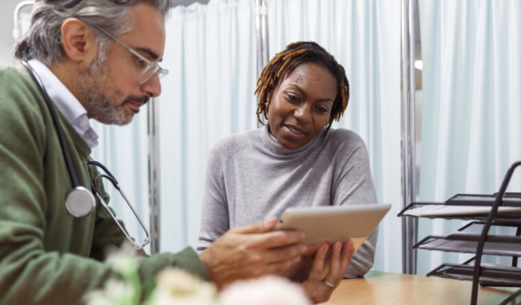 A GP shows a patient something on an iPad