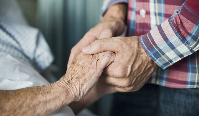 Younger person holding hands of older adult.