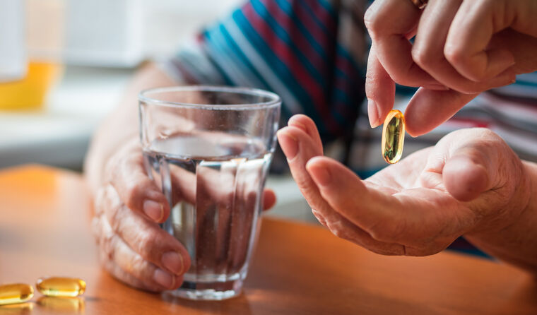 An elderly person holding vitamin D capsules