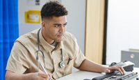 Young male GP working at computer