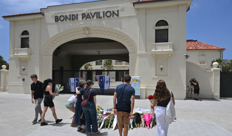 Mourners placing flowers Bondi Beach.