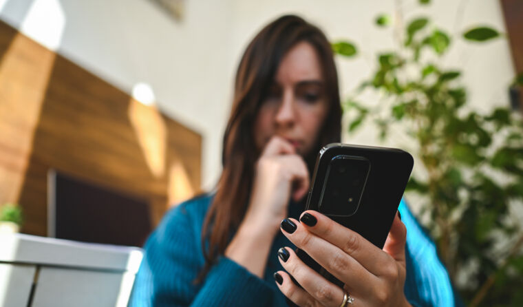 Worried young woman looking at her mobile phone.