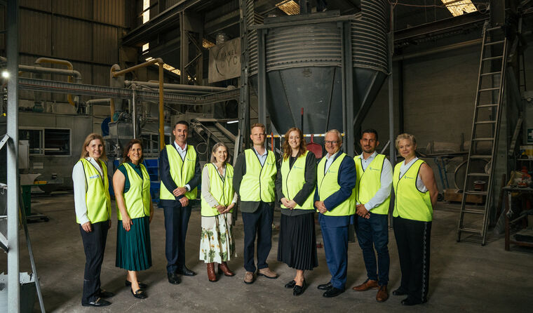 Group of people standing at a recycling plant.