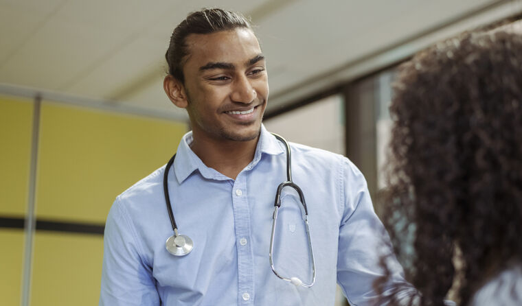 A young male doctor smiles at patient.
