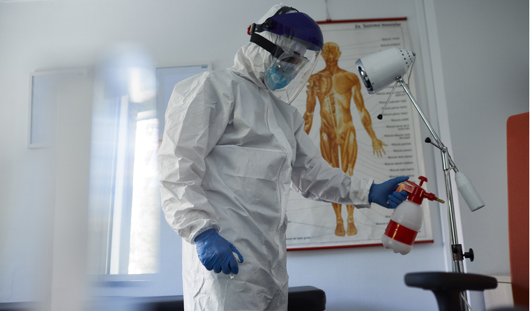 Person in PPE cleaning consulting room.