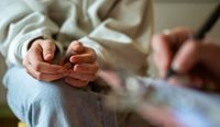 A person sitting anxious with hands on knees