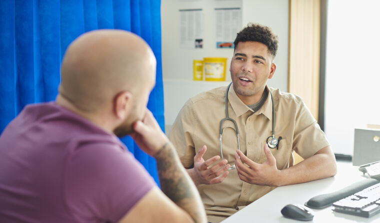 Young male doctor facing man with back to camera