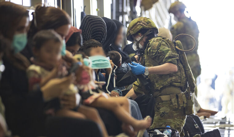 An ADF member attending to women and children.