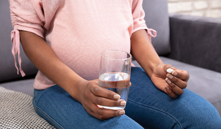 Pregnant woman holding pill and glass of water