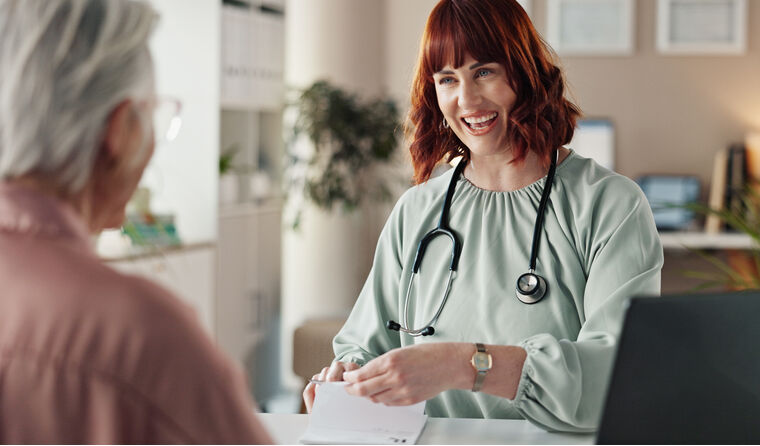Female doctor smiles at patient sitting opposite.