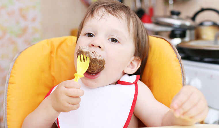 Toddler eating red meat