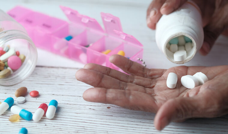 Person tipping medications into their hand. 