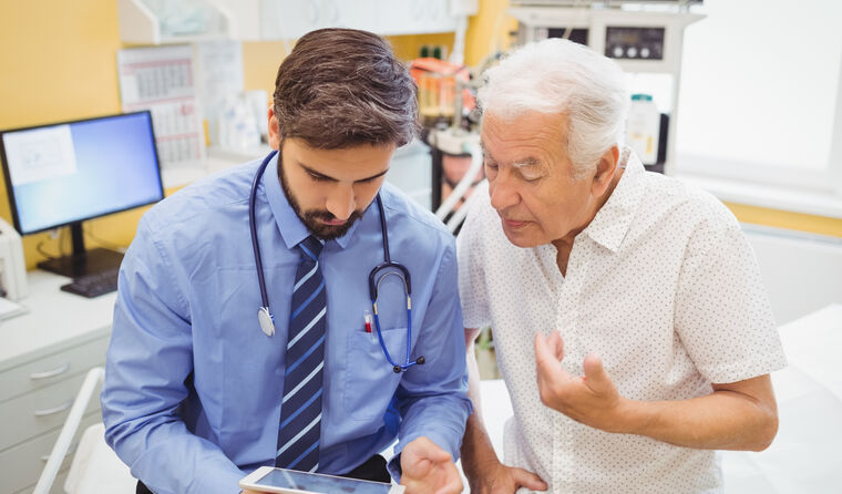 Doctor looking at iPad with older patient 