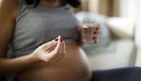 Pregnant woman holding a pill.
