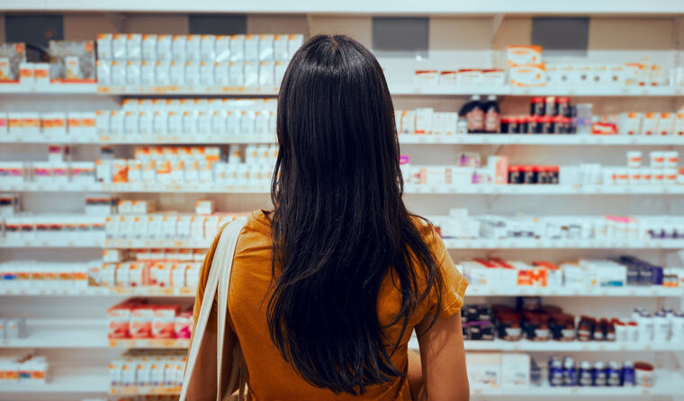 Woman standing in front of pharmacy shelf.