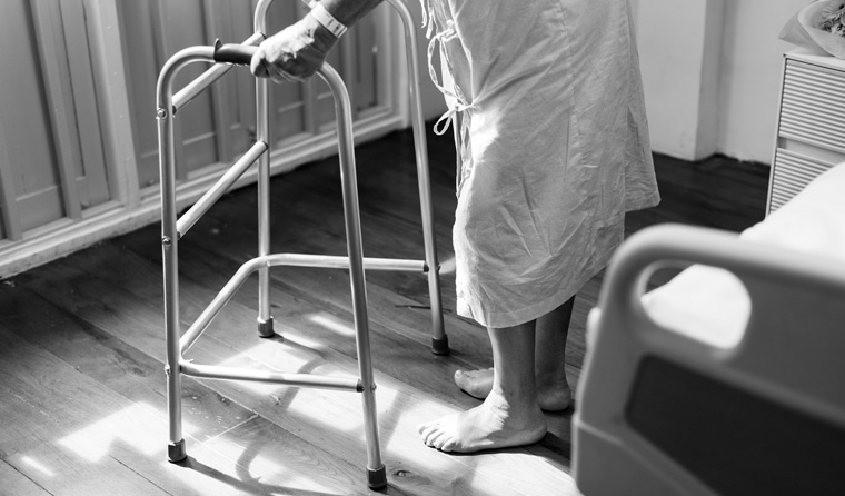 Elderly person standing with support frame.