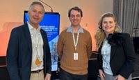 Two men and a woman smile for camera at conference
