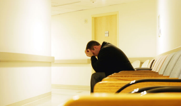 A patient with head in hands in waiting room