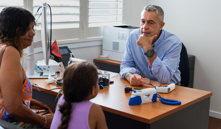 Doctor sits opposite Aboriginal woman and child.