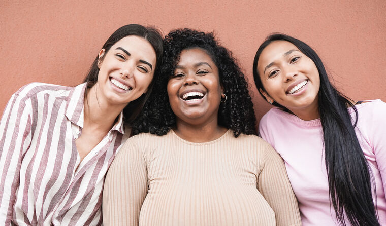 Three women sitting in a row smiling,