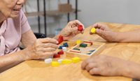 Elderly Asian lady playing with wooden blocks toy.
