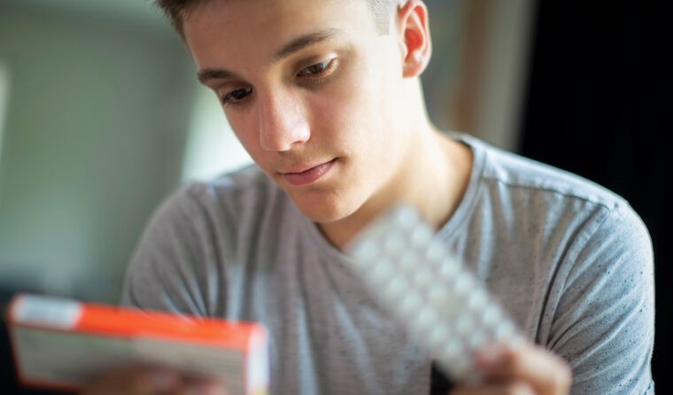 Young man looking at pill packet