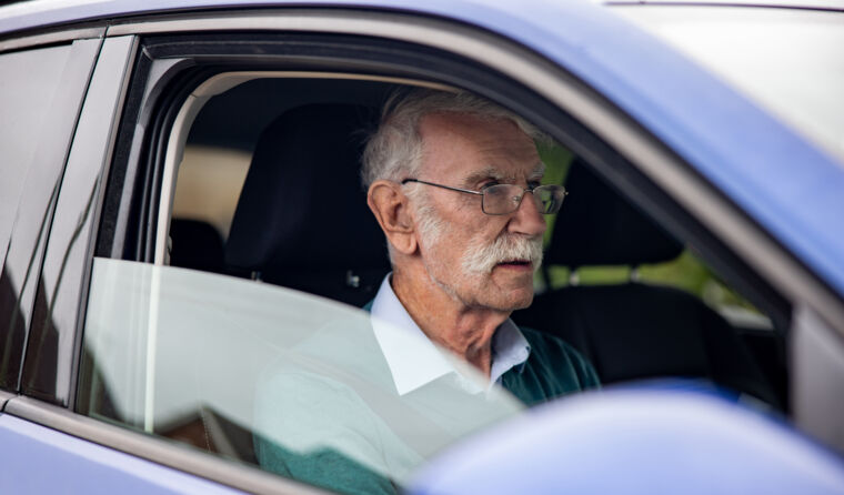 Older man driving a car.