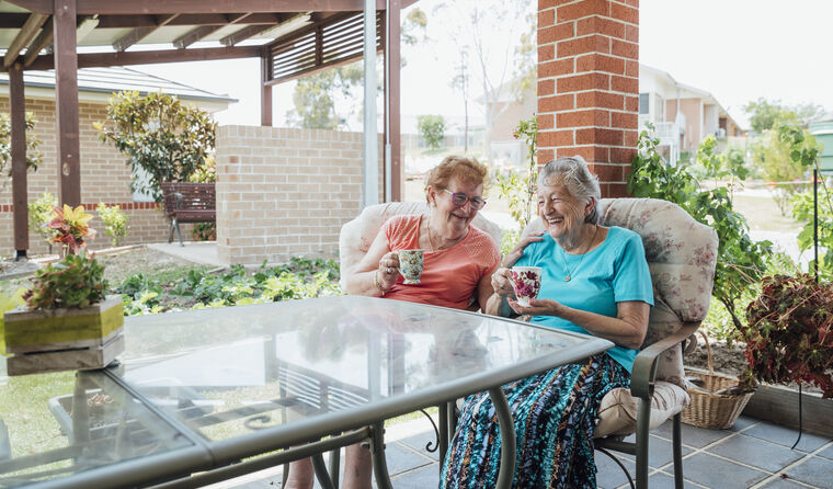 Two elderly women enjoy a cup of tea together.